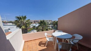 Ein Balkon mit einem weißen Tisch und Stühlen, Blick auf einen Pool und Gebäude im Hintergrund.