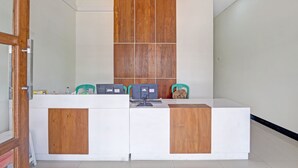 A reception desk with a wooden panel design, two computer stations, and a green chair.