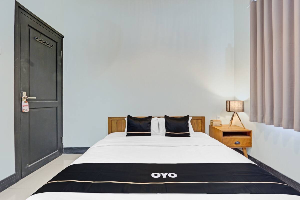 Ein Hotelzimmer mit einem Bett, einem Nachttisch, einer Lampe und einer Tür.