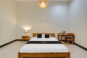 A hotel room with a wooden bed, a bedside table with a lamp, a small desk with a chair, and a hanging light fixture. - Capital O 90811 Myhome (Blora)