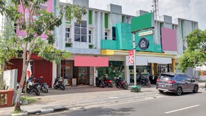 A multi-story building with a storefront, several parked motorcycles, and a car on the street.