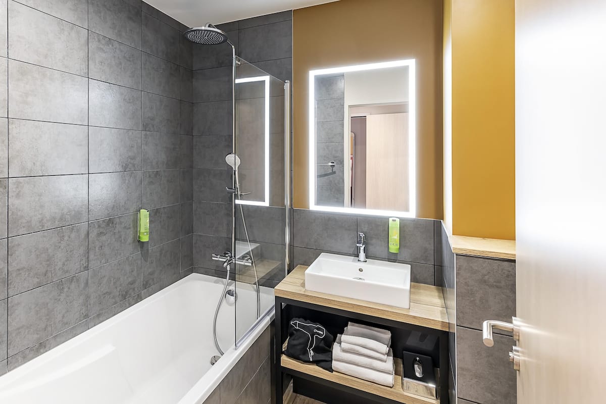 Ein modernes Badezimmer mit einer Badewanne, einer Dusche und einem Waschtisch mit Spiegel.