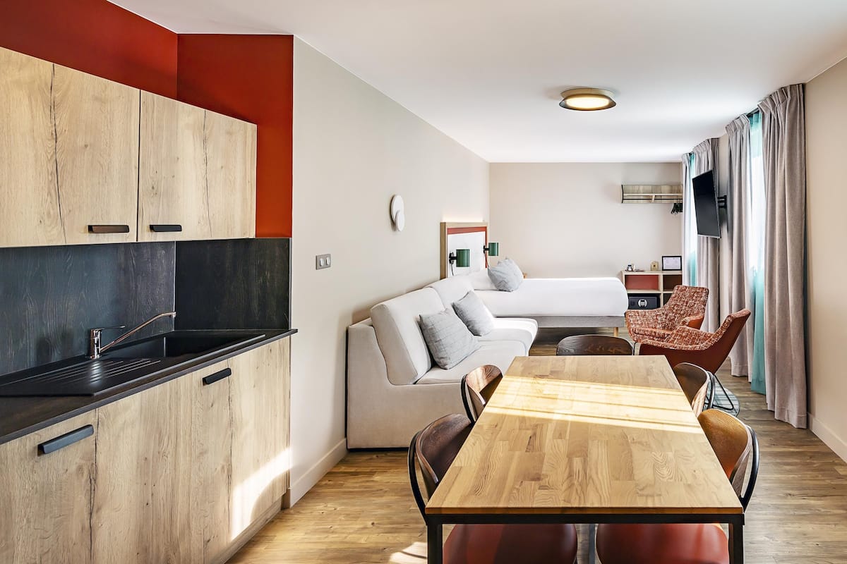 Ein modernes, kompaktes Wohnzimmer mit Küchenzeile, Essbereich und Sitzecke.