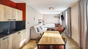 A modern, compact living space with a kitchenette, a dining area, and a seating area.
