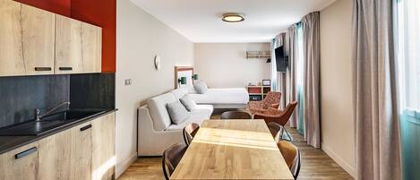 Un espacio habitable moderno y funcional con kitchenette, comedor y zona de estar.