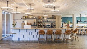 A modern bar area with a central counter, bar stools, and overhead lighting.