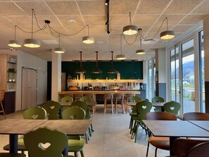 Enjoy meals and social gatherings in this stylish dining area with a central bar, comfortable seating, and large windows offering a view of the outdoors.