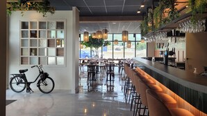 A modern bar area with a wet floor, a bicycle, and a bar counter with glasses. - Best Western Coeur de Maurienne Hotel Restaurant & Spa (Saint-Jean-de-Maurienne)