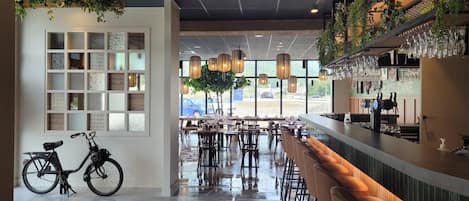 A modern bar area with a wet floor, a bicycle, and a bar counter with glasses.
