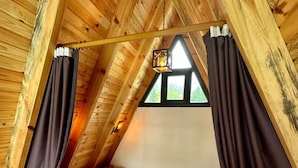 A wooden cabin with a loft-style bed, a small window, and a hanging light fixture. - Sapanca Rose Garden Bungalov (Sapanca)