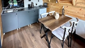 A compact kitchen with modern appliances, a dining area with a wooden table and chairs, and a sloped ceiling with exposed wooden beams. - Sapanca Rose Garden Bungalov (Sapanca)