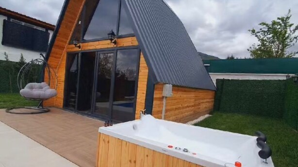 A modern, triangular-shaped building with a large glass door and a hot tub in the backyard. - Sapanca Rose Garden Bungalov (Sapanca)