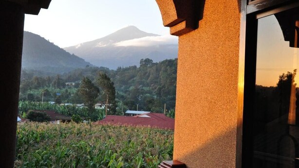 Une vue à travers une porte en arc sur un paysage rural, avec une montagne en arrière-plan.