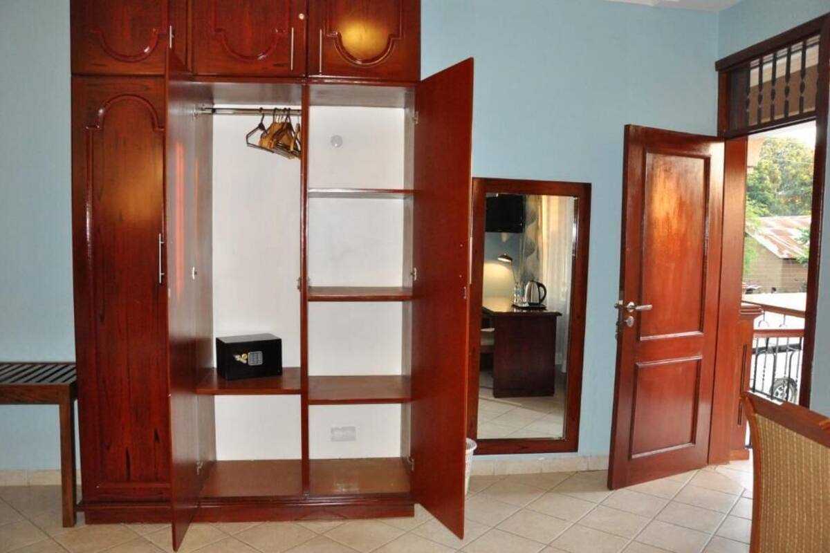 A room with a wooden wardrobe, a mirror, and a door leading to an outdoor area.