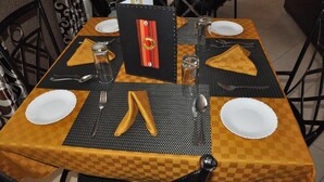 Une table à manger dressée avec une nappe à carreaux, des sets de table noirs et une carte décorative placée au centre.