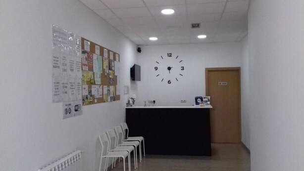 A reception area with a clock, bulletin board, chairs, and a counter.