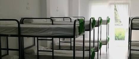 Un dormitorio con literas, paredes blancas y techo de baldosas.