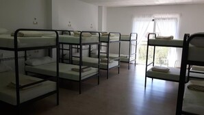 A dormitory room with bunk beds arranged in two rows.
