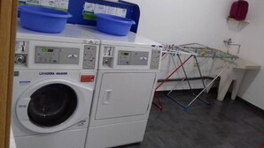 A laundry area with a front-loading washing machine, a drying rack, and a sink.