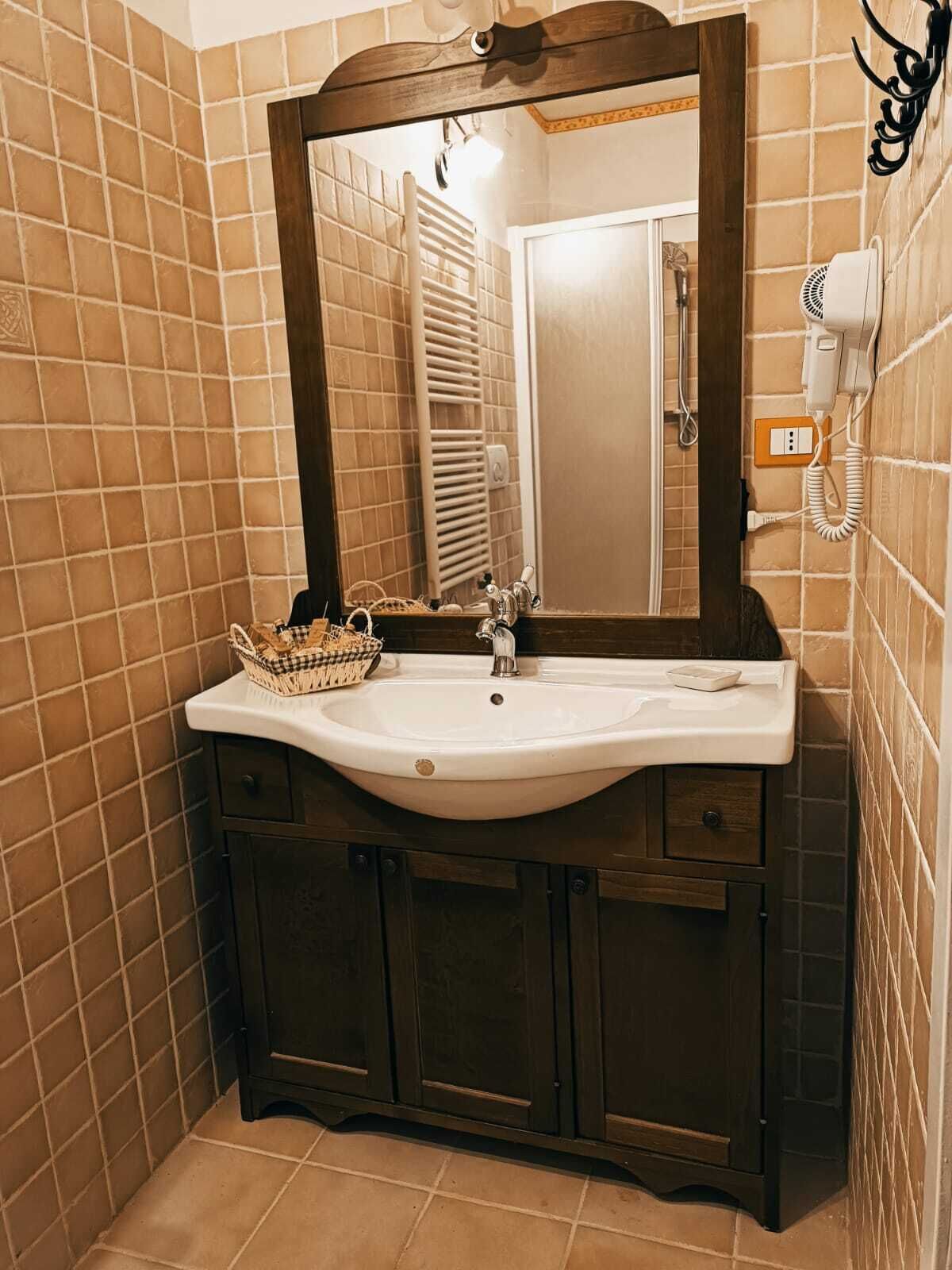 Un baño con un lavamanos blanco, armarios de madera oscura y un espejo con marco de madera.