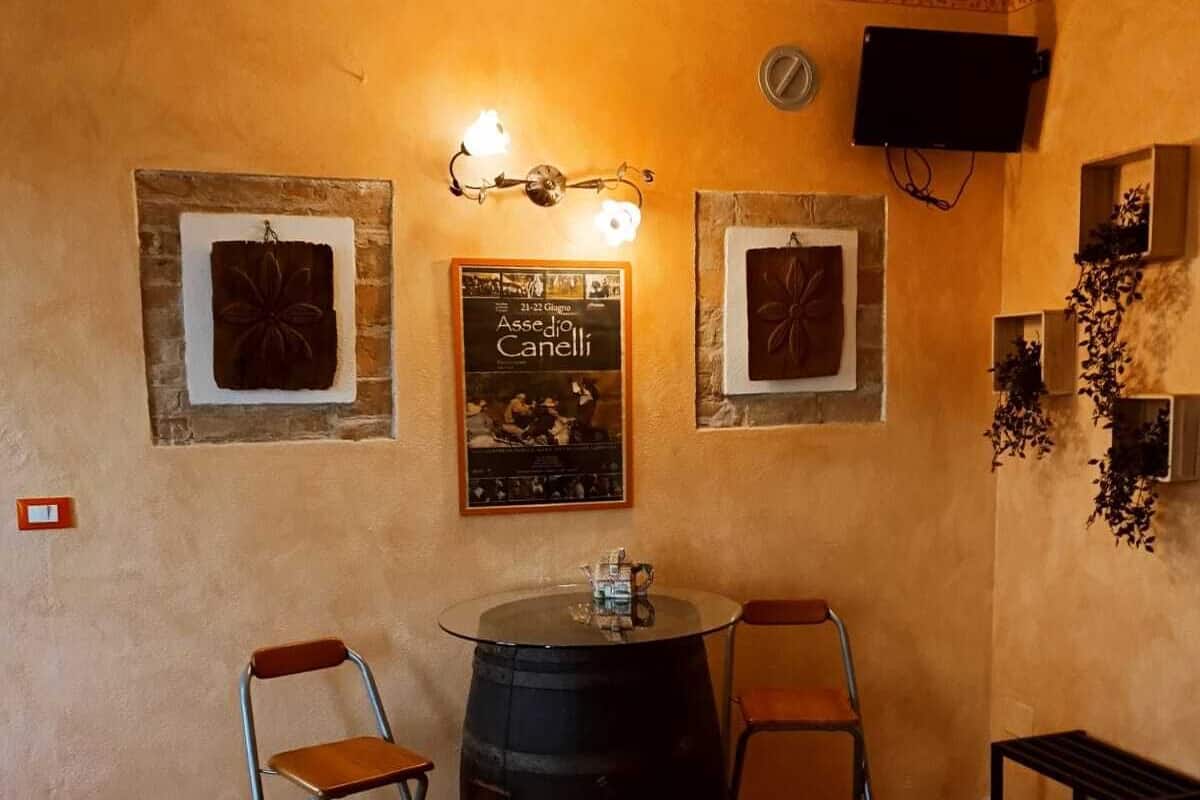 A room with a wooden floor, two metal chairs, a round table with a barrel, and a poster on the wall.