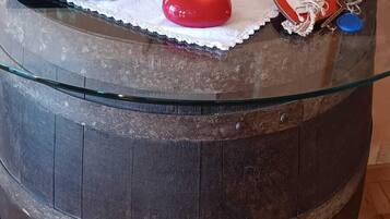Una mesa rústica de madera con cubierta de vidrio, decorada con una variedad de quesos, embutidos y pequeños pasteles.