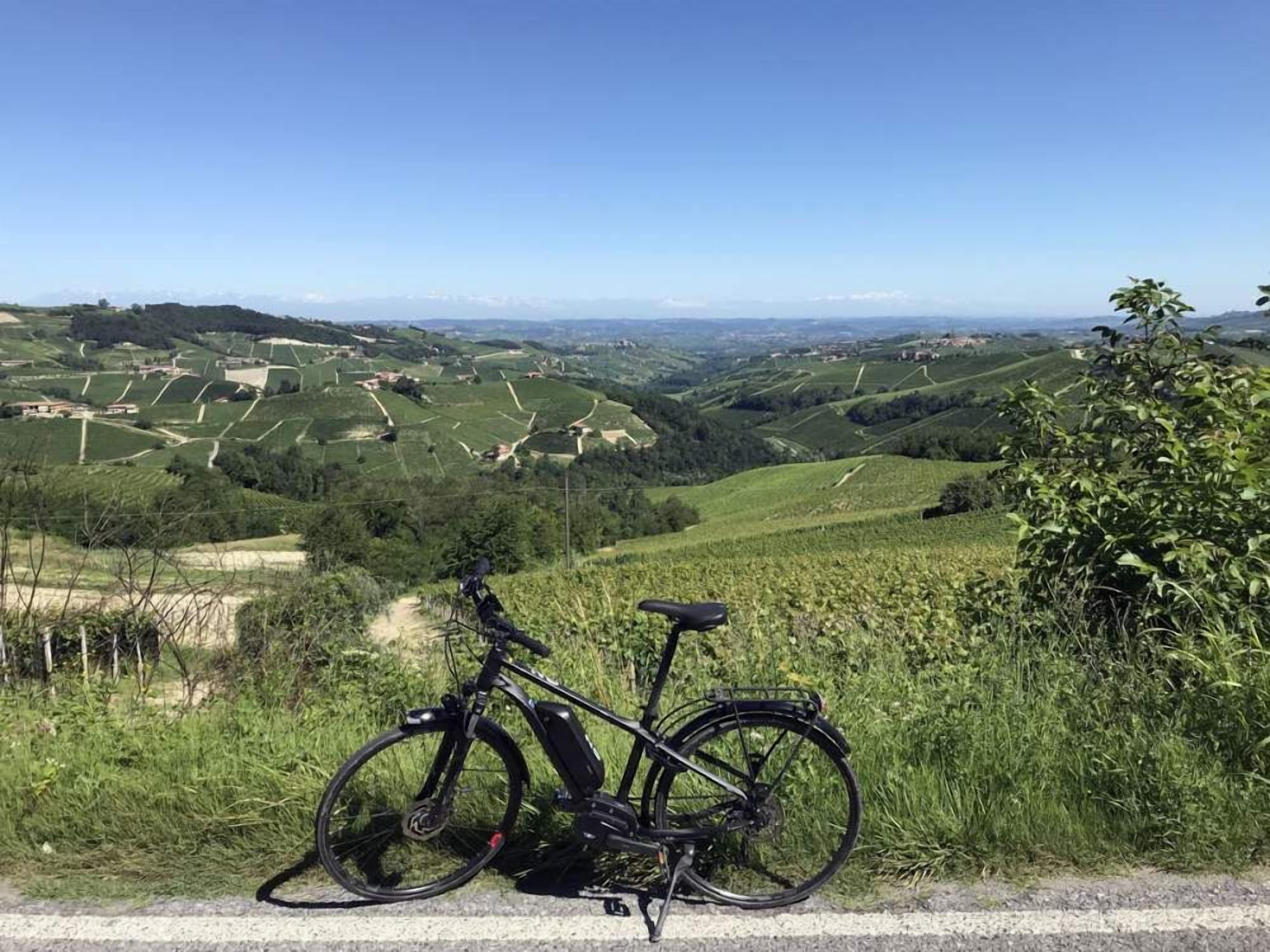 A bicycle parked on a rural road with a view of rolling hills and fields.