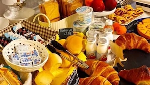 A buffet table with various food items including pastries, fruits, and dairy products.