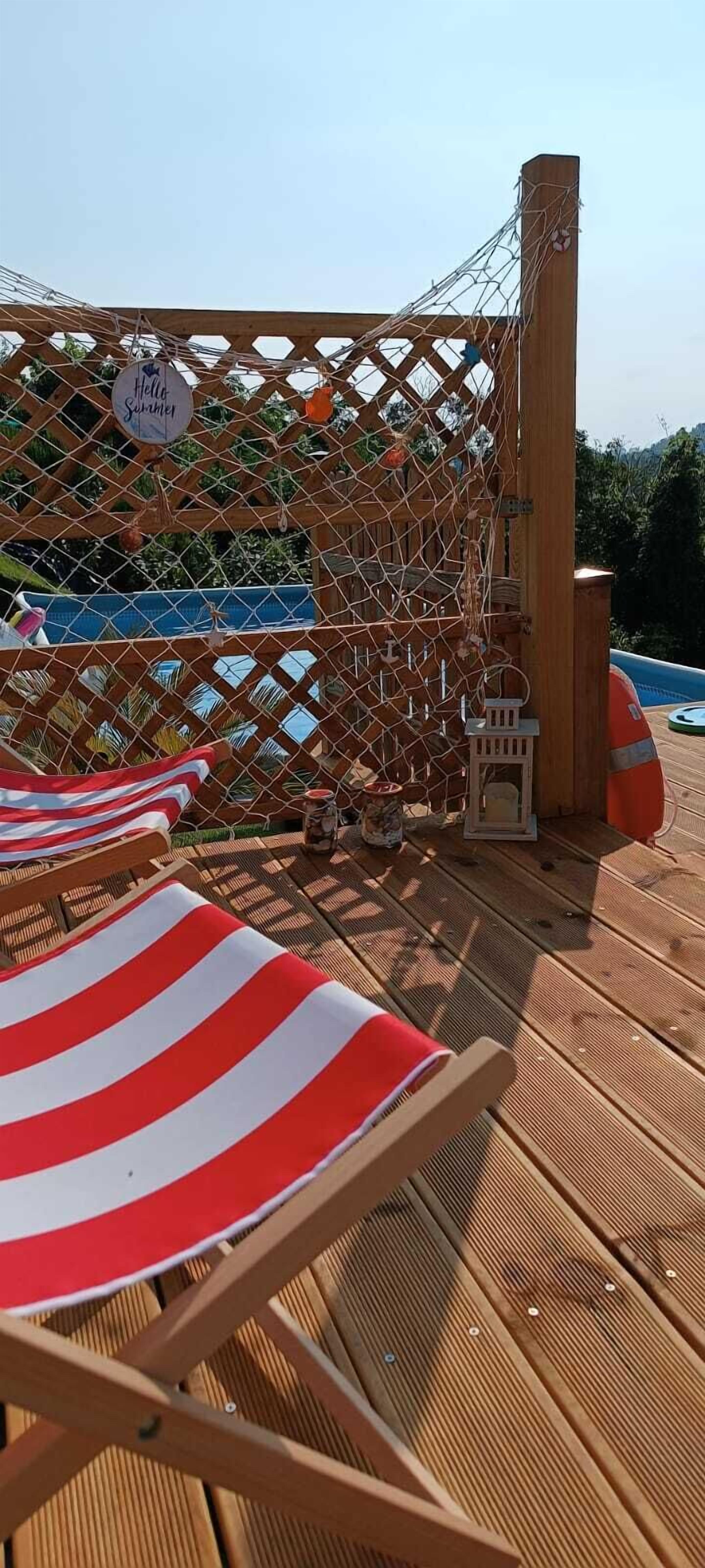 Una terraza con sillones de madera y una barandilla de cuerda.