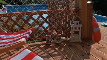 Una terraza con sillones de madera y una barandilla de cuerda.