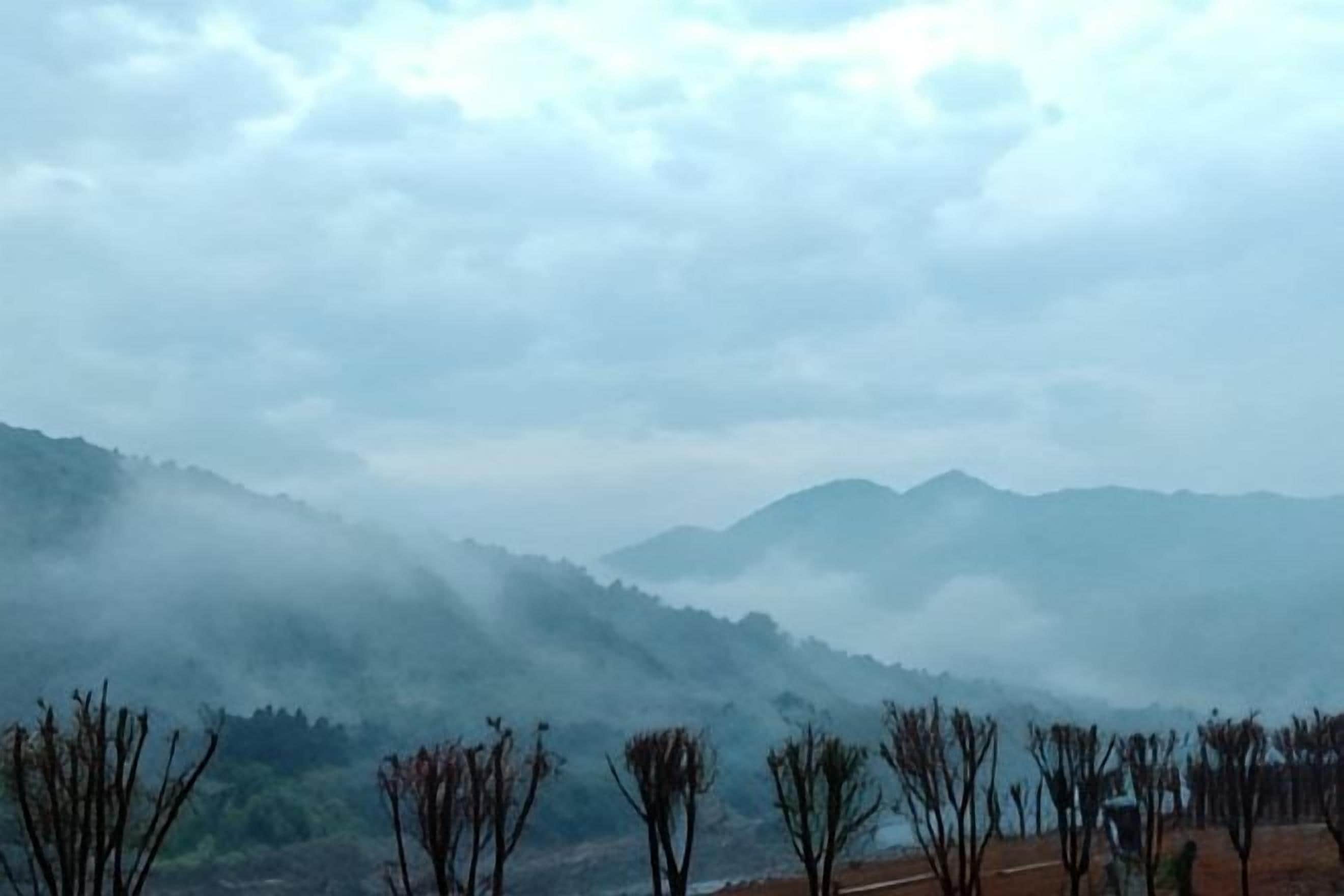 Un paisaje montañoso con picos cubiertos de niebla y vegetación escasa.