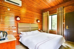 Una habitación con paneles de madera, una cama, una mesita de noche, una tetera y una ventana con cortinas.