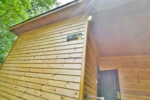 Una cabaña de madera con una puerta visible y un letrero que indica un número de habitación.