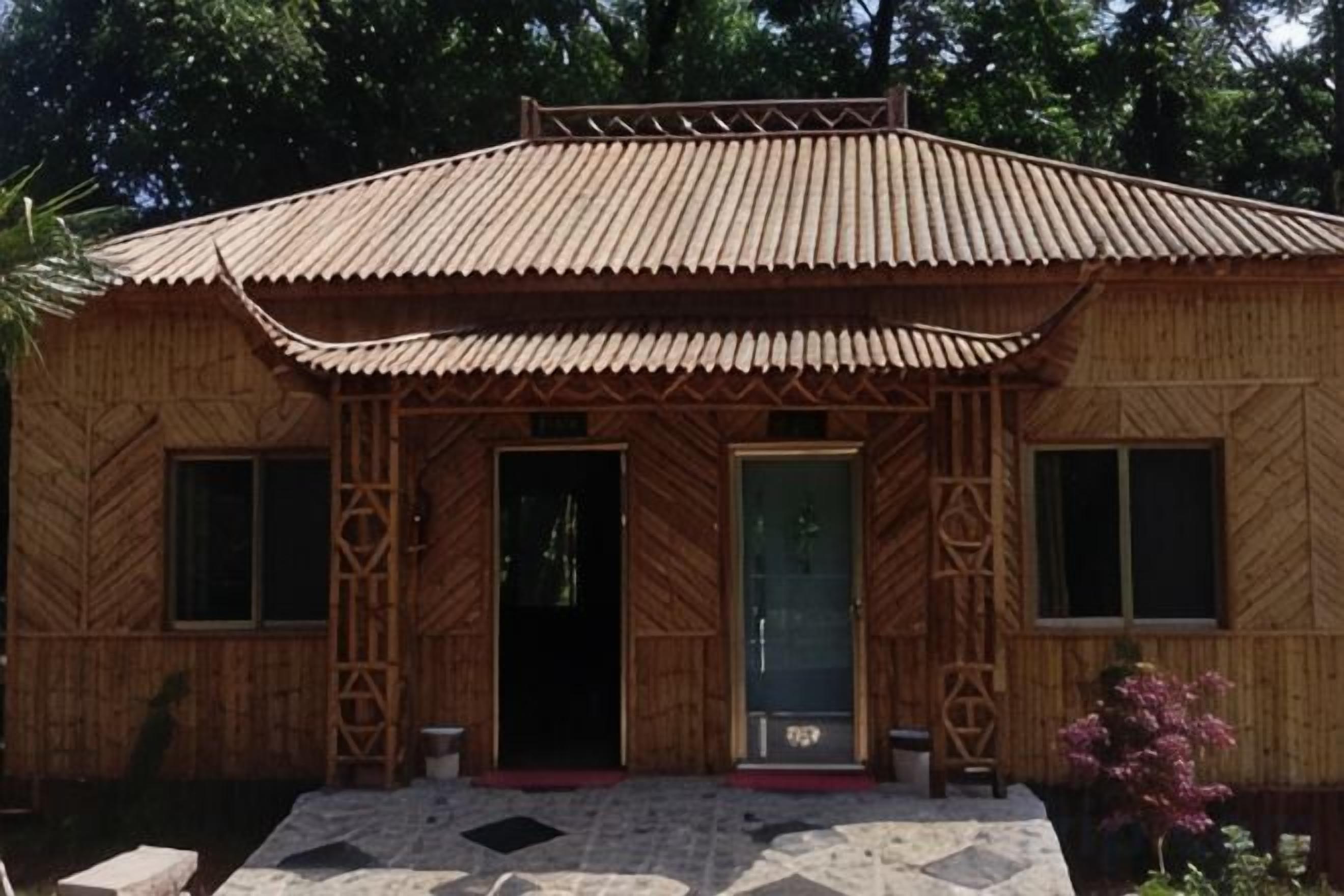 A bamboo house with a tiled entrance and a metal roof.