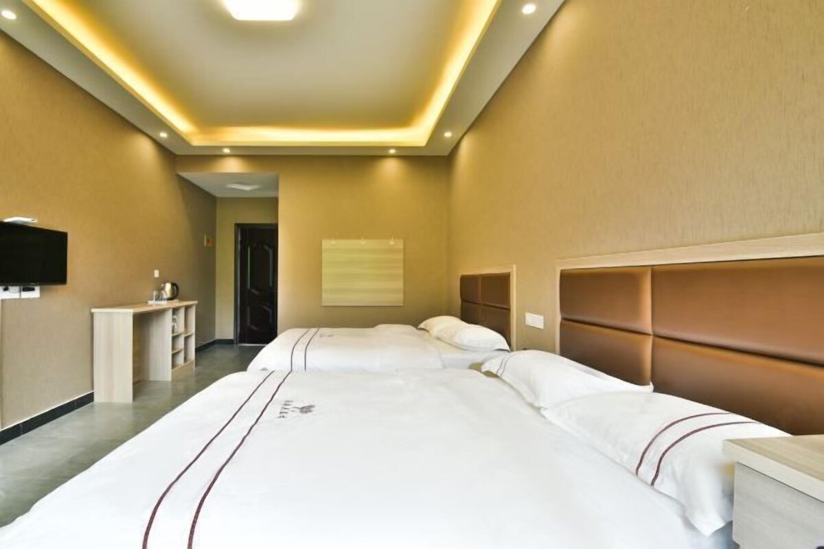 Habitación de hotel con dos camas, televisión, escritorio y una puerta que da a otra habitación.