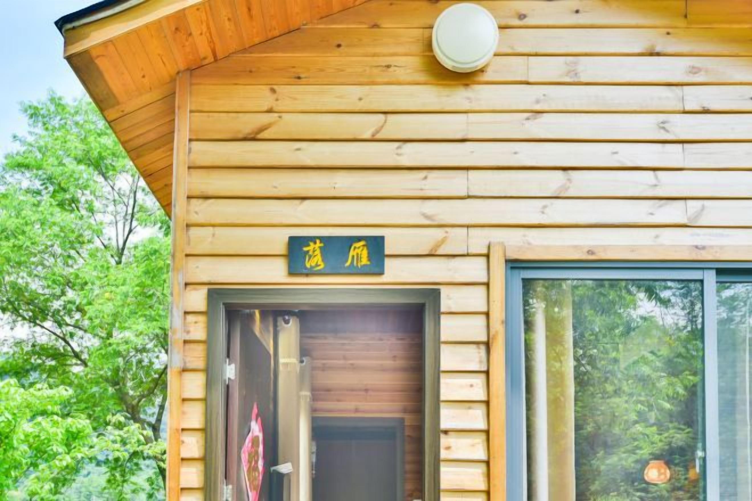 A wooden cabin with a visible entrance door and a sign above it.