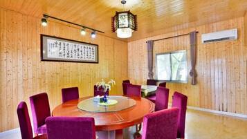 Una habitación con paneles de madera, una mesa redonda y sillas, un cuadro en la pared y una ventana con cortinas.
