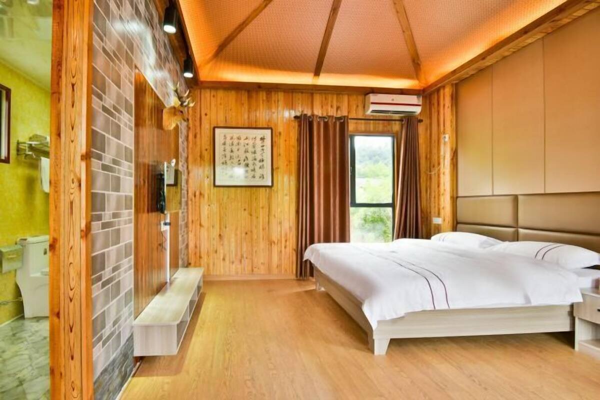 A wooden-themed room with a bed, a bench, and a window.