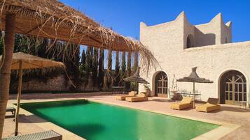 Relax by the serene pool surrounded by lounge chairs and a shaded area.