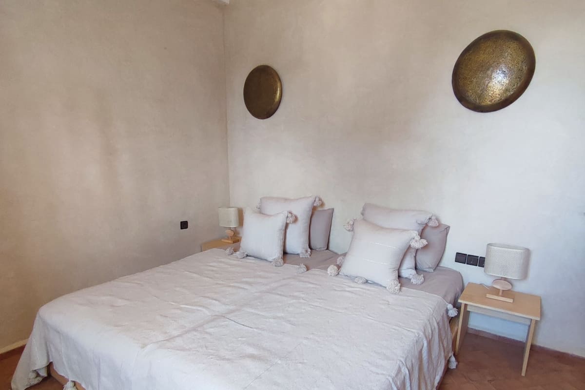 A bedroom with a large bed, two bedside tables, and a wall-mounted lamp.