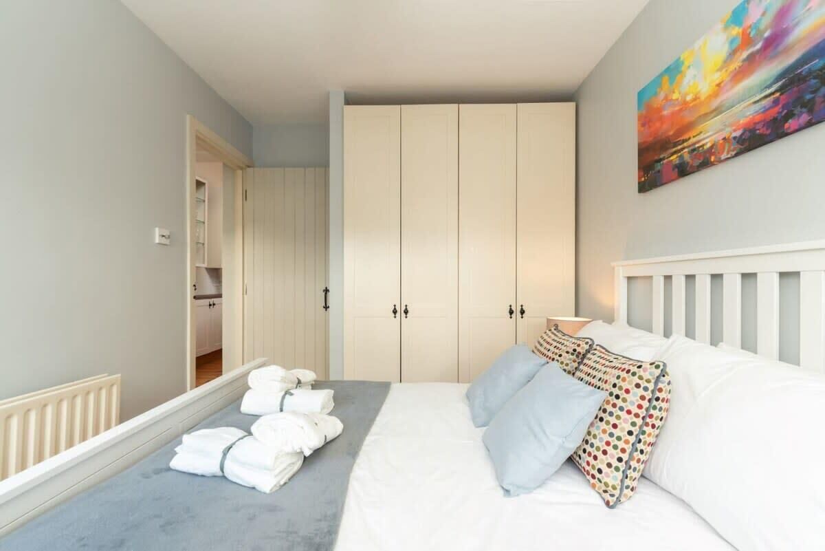 Una camera da letto con un letto, cuscini, un armadio e un quadro appeso al muro.