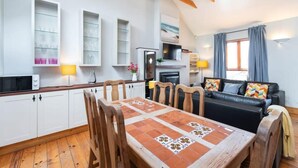Ein modernes Wohnzimmer mit einem schwarzen Ledersofa, einem Holzespeisetisch und weißen Schränken.