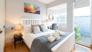 Ein Schlafzimmer mit Bett, Nachttisch, Lampe und einem Bild an der Wand.