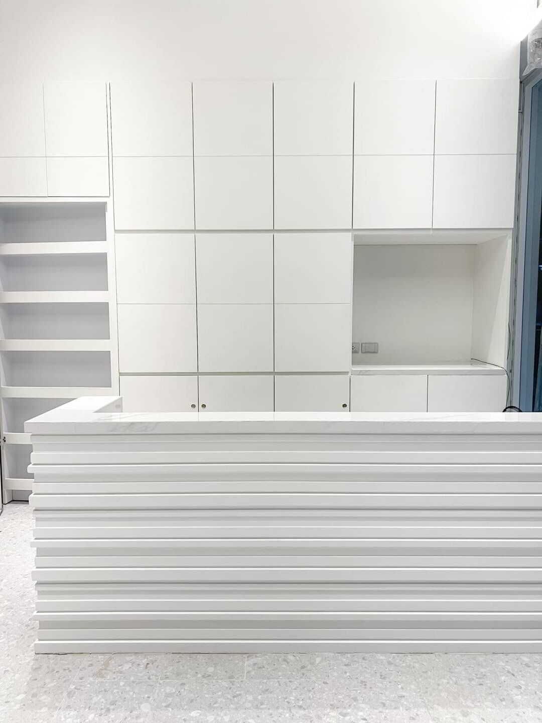 A white, modern storage unit with multiple compartments and a built-in bench.