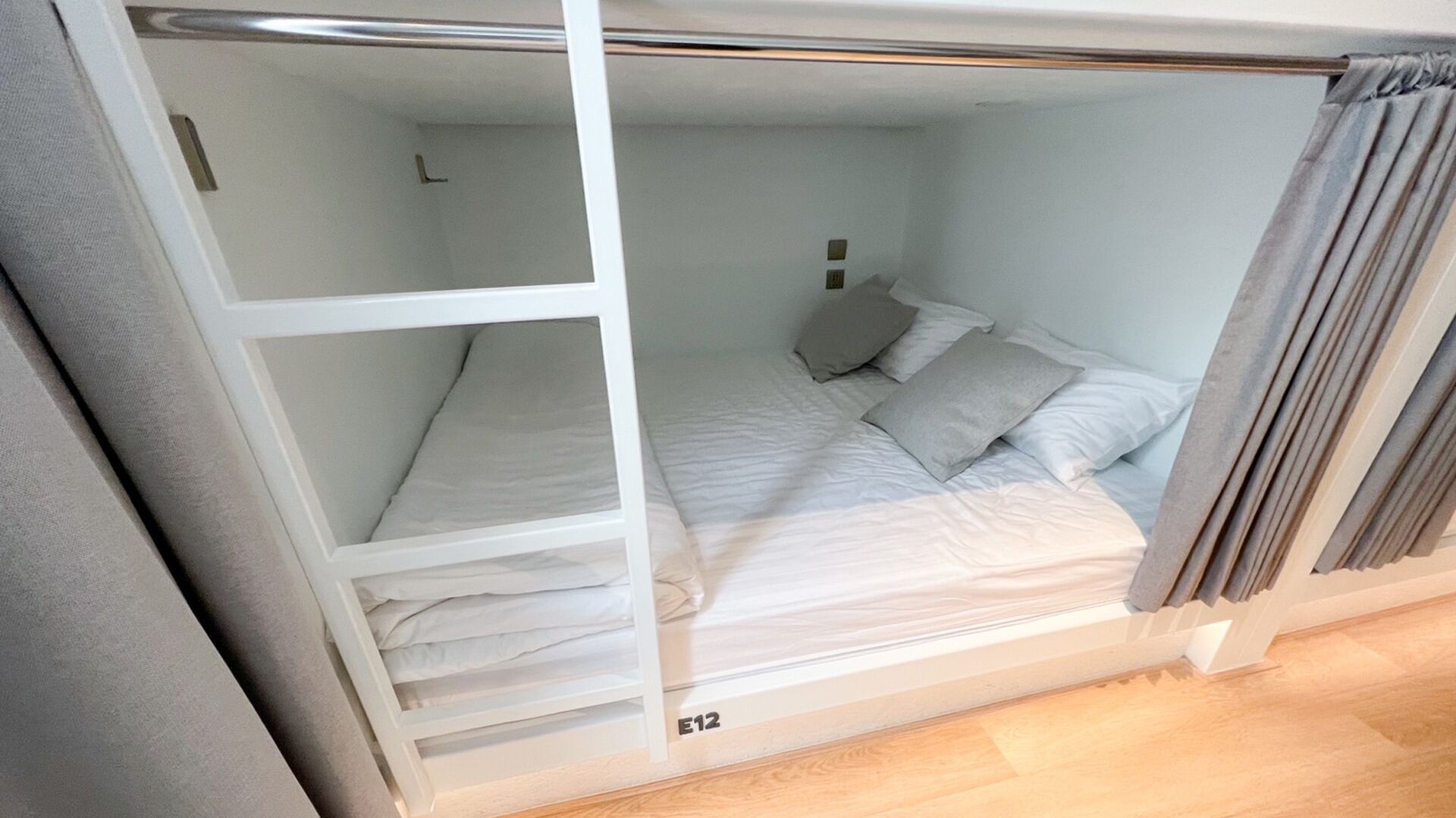A single-bed room with a bunk bed, a bedside table, and a lamp.