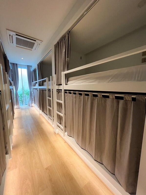 A narrow hallway with bunk beds, wooden flooring, and curtains on the windows. - MatiniGrandStation (Bangkok)