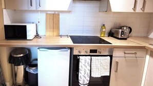 Eine kompakte Küchenzeile mit Mikrowelle, Toaster, Wasserkocher und kleinem Kühlschrank.