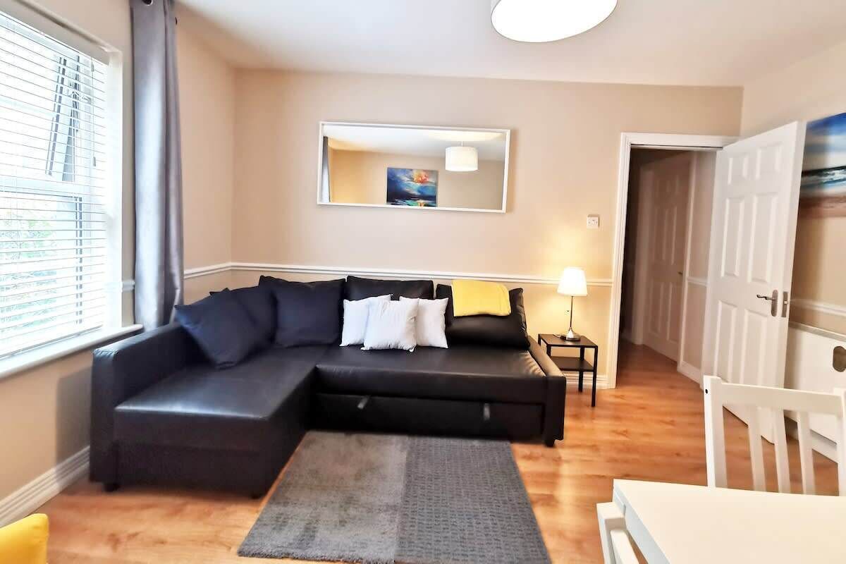 A living room with a sectional sofa, a small table, a lamp, and a painting on the wall.