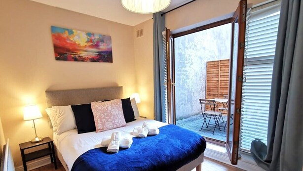 Una camera da letto con un letto, un comodino, un quadro e vista su uno spazio esterno con tavolo e sedie.