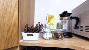 Eine Küchenarbeitsplatte mit einer Kaffeemaschine, einer Kaffeepackung und Zuckerdosen sowie Gewürzgläsern.